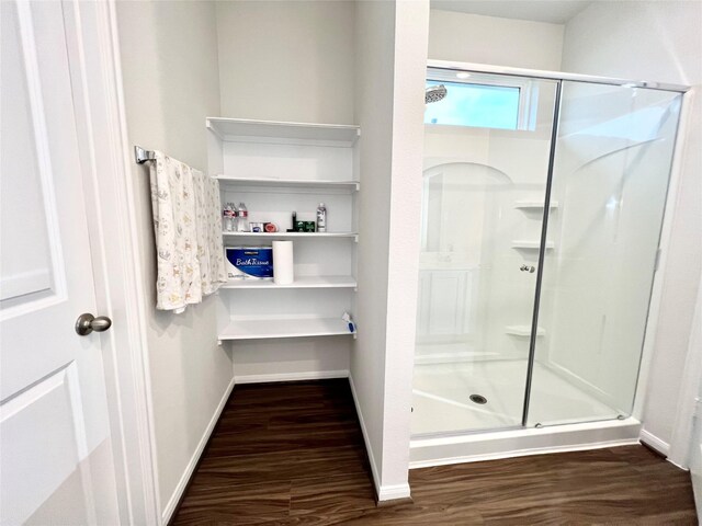bathroom featuring wood finished floors, baseboards, and a stall shower