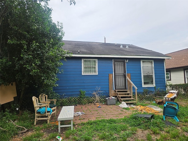 rear view of property with roof with shingles, a patio area, and entry steps
