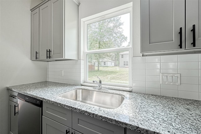 kitchen featuring a sink, stainless steel dishwasher, gray cabinetry, and backsplash