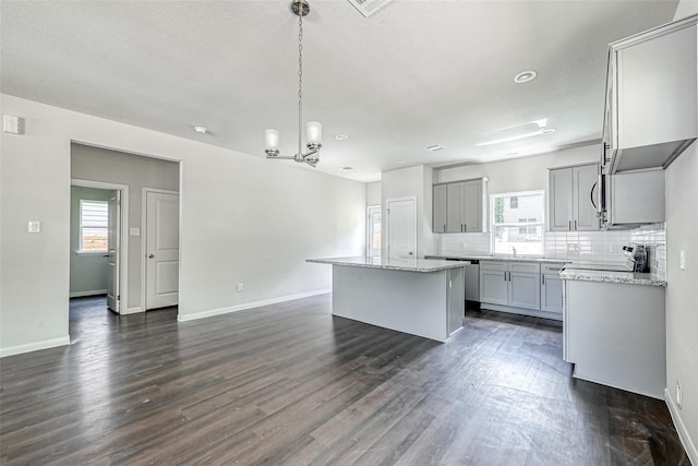 kitchen featuring a notable chandelier, decorative backsplash, a kitchen island, gray cabinetry, and dark wood-style floors