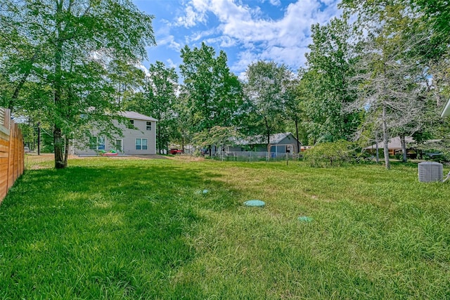 view of yard featuring central AC and fence