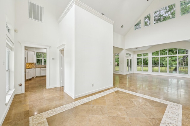 unfurnished living room featuring baseboards, visible vents, and a towering ceiling