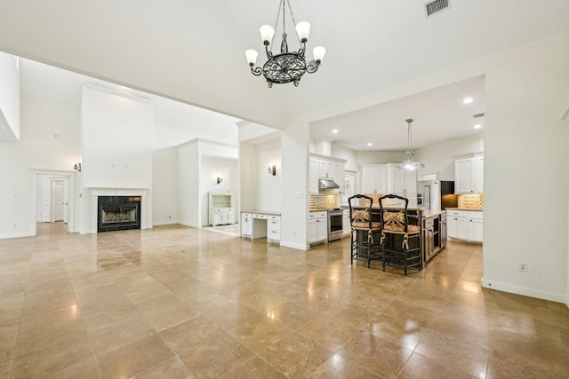 living area with a towering ceiling, visible vents, baseboards, a notable chandelier, and recessed lighting