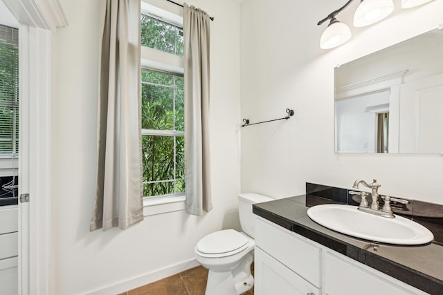 bathroom featuring vanity, baseboards, tile patterned flooring, and toilet
