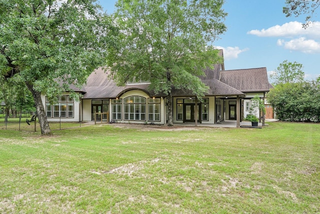 rear view of house with a yard, fence, a shingled roof, and a patio area