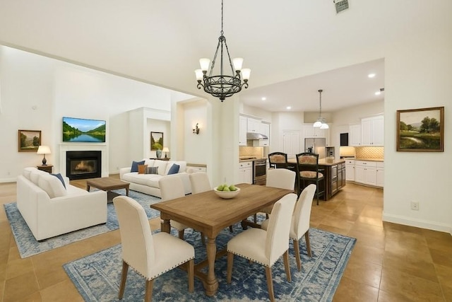 12061 Oak Forest Ln, Conroe, TX 77385 - dining area with light tile patterned floors, a chandelier, recessed lighting, a towering ceiling, and a glass covered fireplace