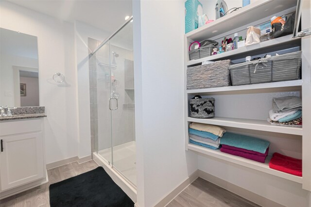 bathroom featuring vanity, baseboards, wood finished floors, and a shower stall