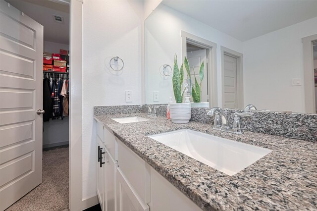full bathroom with a sink, a spacious closet, double vanity, and visible vents