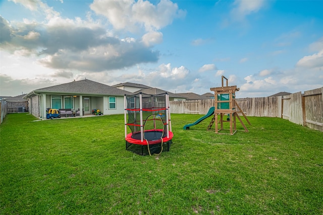 view of play area with a lawn, a patio, a fenced backyard, and a trampoline