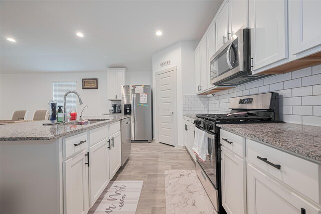 kitchen featuring a sink, light stone counters, stainless steel appliances, recessed lighting, and white cabinetry