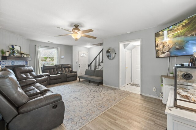 living area featuring a ceiling fan, visible vents, a fireplace, baseboards, and light wood-style floors