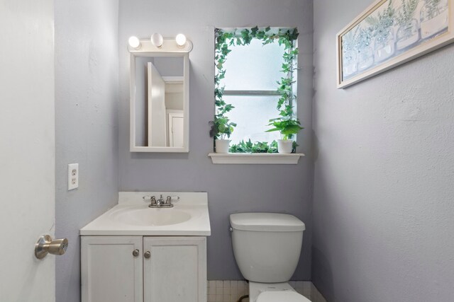 half bath featuring vanity and toilet