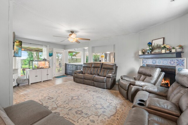 living room with a ceiling fan, wood finished floors, and a tile fireplace