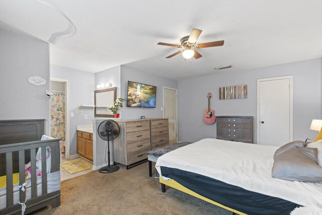 carpeted bedroom with visible vents, a ceiling fan, and ensuite bathroom