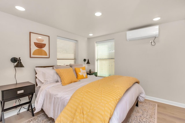 bedroom with recessed lighting, wood finished floors, baseboards, and an AC wall unit