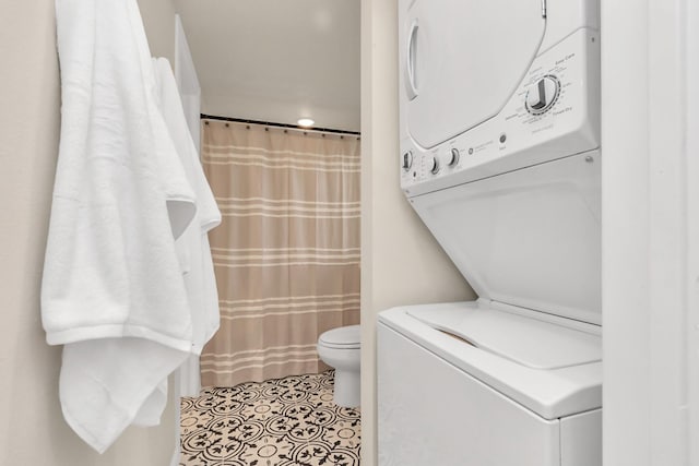 full bath featuring stacked washer and clothes dryer, a shower with curtain, toilet, and tile patterned floors