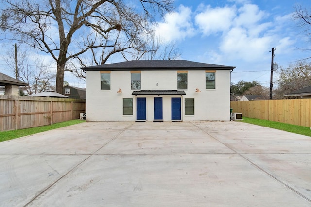 rear view of property with a fenced backyard, concrete driveway, a patio, and stucco siding