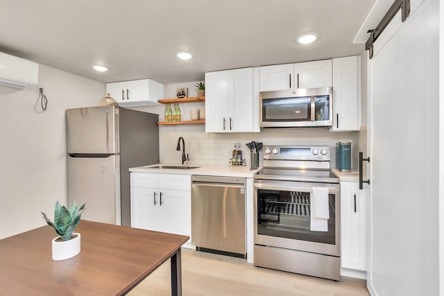 kitchen with a sink, stainless steel appliances, white cabinetry, light wood-style floors, and tasteful backsplash