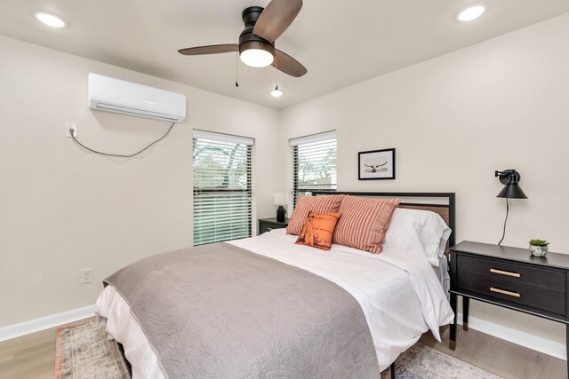 bedroom featuring wood finished floors, baseboards, a wall mounted AC, and recessed lighting