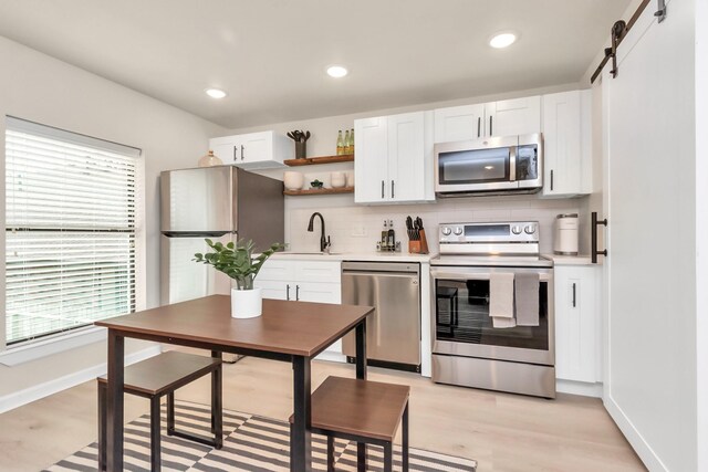 1747 Forest Hill Blvd, Houston, TX 77023 - kitchen featuring stainless steel appliances, a sink, decorative backsplash, light countertops, and white cabinets