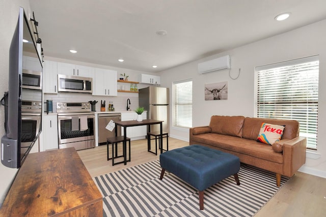 living area featuring a wall mounted air conditioner, light wood-type flooring, baseboards, and recessed lighting
