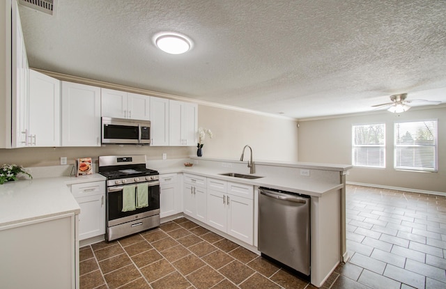 1211 Reedpoint Dr, Houston, TX 77090 - kitchen featuring a sink, light countertops, a textured ceiling, stainless steel appliances, and a peninsula