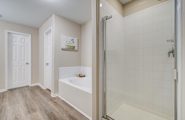 1211 Reedpoint Dr, Houston, TX 77090 - bathroom featuring a textured ceiling, wood finished floors, a garden tub, and a stall shower