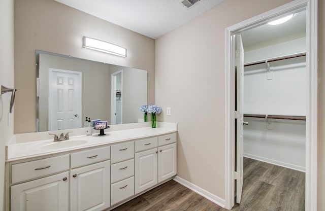 1211 Reedpoint Dr, Houston, TX 77090 - bathroom featuring a walk in closet, visible vents, wood finished floors, and vanity