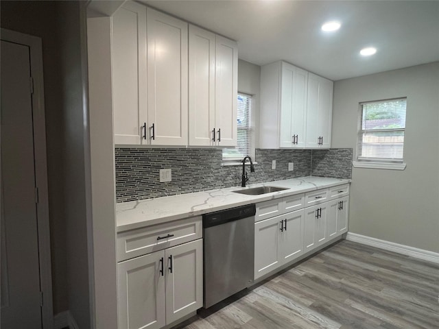 4409 Saint Goar St, Dickinson, TX 77539 - kitchen with stainless steel dishwasher, a sink, decorative backsplash, baseboards, and white cabinetry