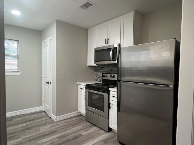 4409 Saint Goar St, Dickinson, TX 77539 - kitchen with stainless steel appliances, light wood-type flooring, white cabinets, baseboards, and tasteful backsplash