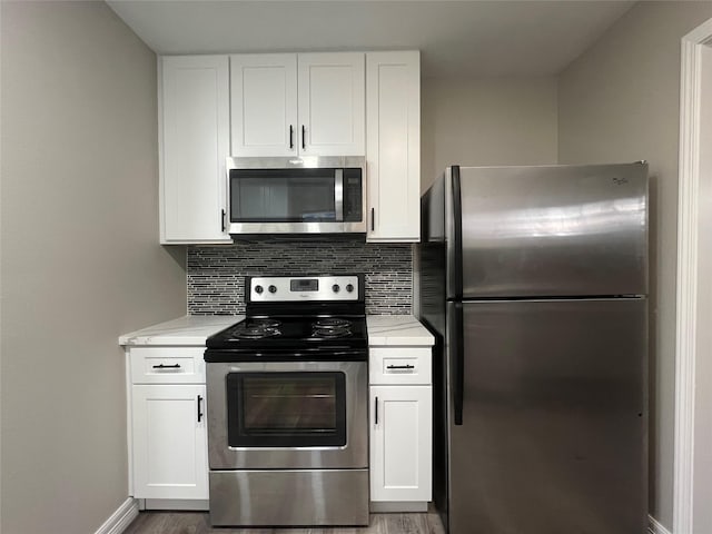4409 Saint Goar St, Dickinson, TX 77539 - kitchen with stainless steel appliances, backsplash, white cabinetry, and wood finished floors