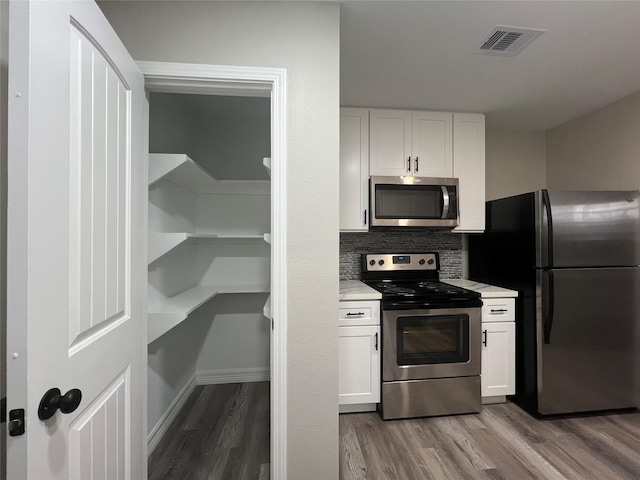 4409 Saint Goar St, Dickinson, TX 77539 - kitchen with appliances with stainless steel finishes, wood finished floors, light countertops, and white cabinets