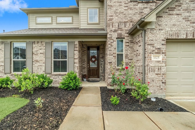 property entrance with brick siding, an attached garage, and a shingled roof