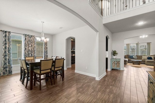 dining room featuring dark wood-style flooring, arched walkways, baseboards, and a chandelier