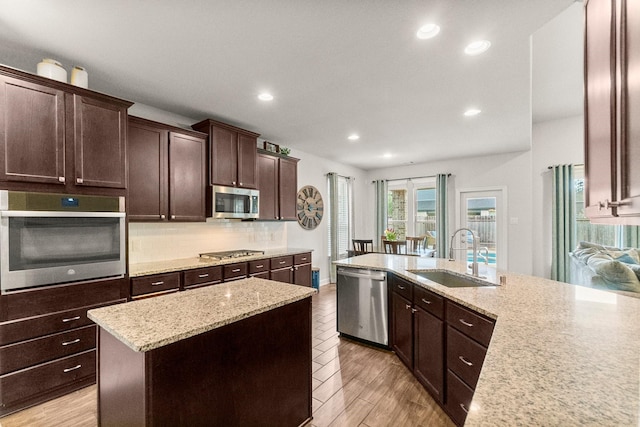 kitchen with dark brown cabinetry, appliances with stainless steel finishes, a sink, recessed lighting, and decorative backsplash