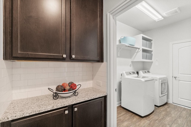 washroom featuring separate washer and dryer, visible vents, and light wood-style floors