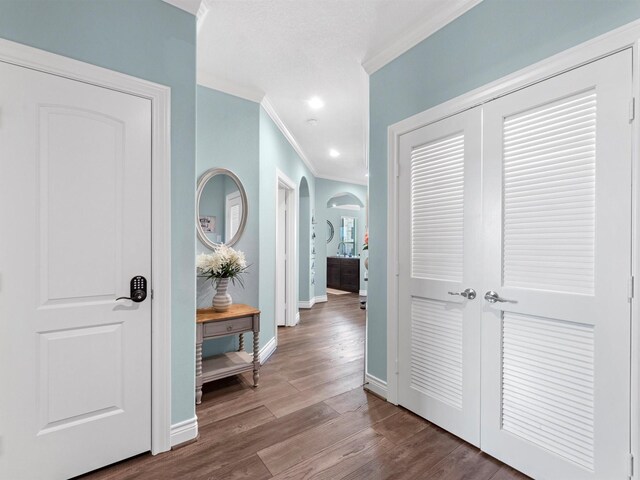 hall with ornamental molding, wood finished floors, baseboards, recessed lighting, and arched walkways