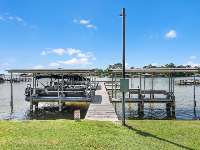 dock area featuring a lawn, boat lift, and a water view