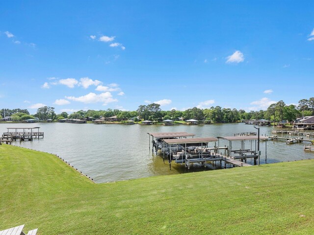 dock area with boat lift, a water view, and a yard