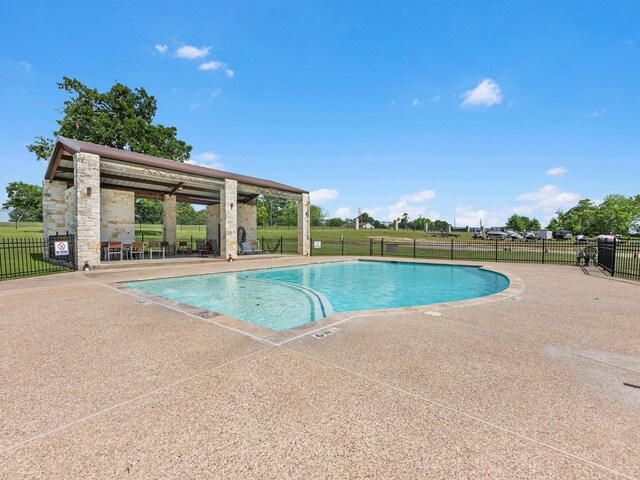 community pool with a patio area and fence