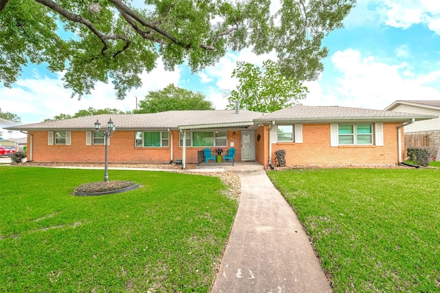 ranch-style home featuring covered porch, brick siding, and a front yard
