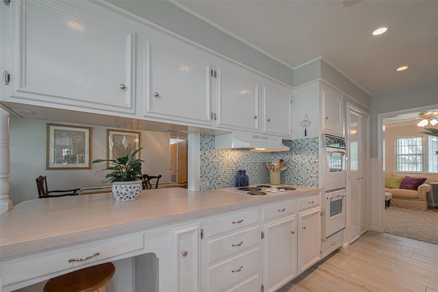 kitchen with stainless steel double oven, under cabinet range hood, white electric stovetop, and white cabinetry