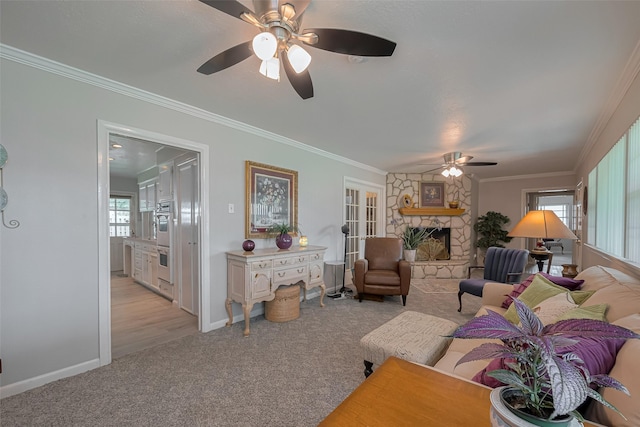 living area featuring a ceiling fan, crown molding, a fireplace, baseboards, and light carpet