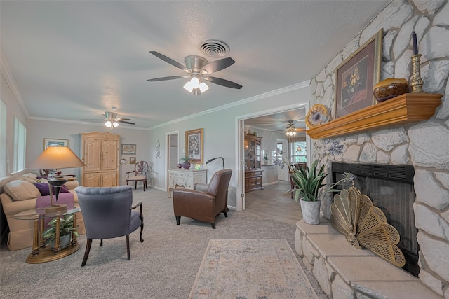 living room with crown molding, ceiling fan, visible vents, and a fireplace