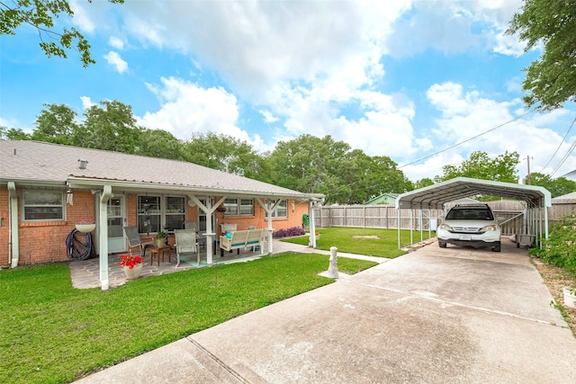 view of yard with a detached carport, fence, concrete driveway, a patio, and outdoor lounge area