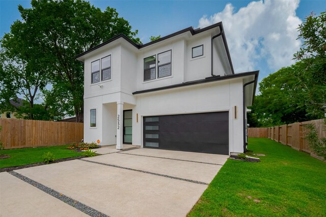 modern home featuring an attached garage, a front lawn, stucco siding, and fence