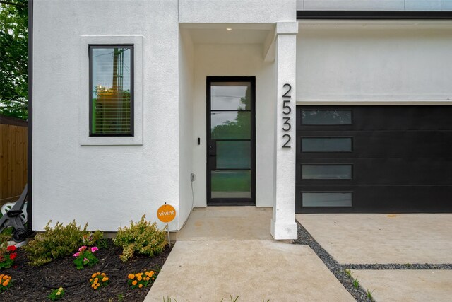 entrance to property with an attached garage and stucco siding