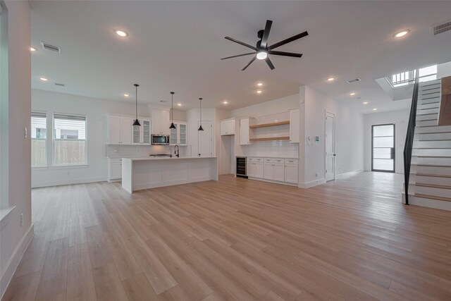 unfurnished living room with plenty of natural light, a ceiling fan, recessed lighting, and light wood-style flooring