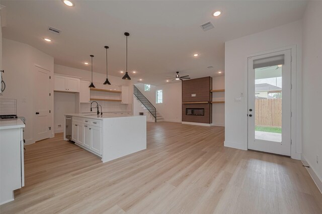 kitchen featuring stainless steel dishwasher, a ceiling fan, visible vents, and a large fireplace