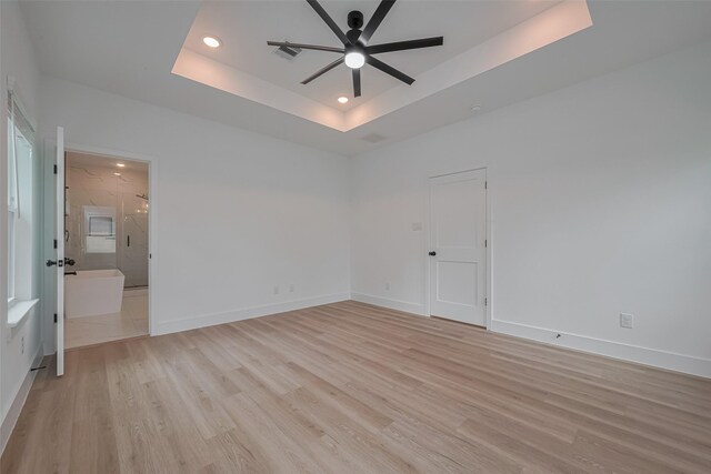 empty room with visible vents, ceiling fan, recessed lighting, a tray ceiling, and light wood-style flooring